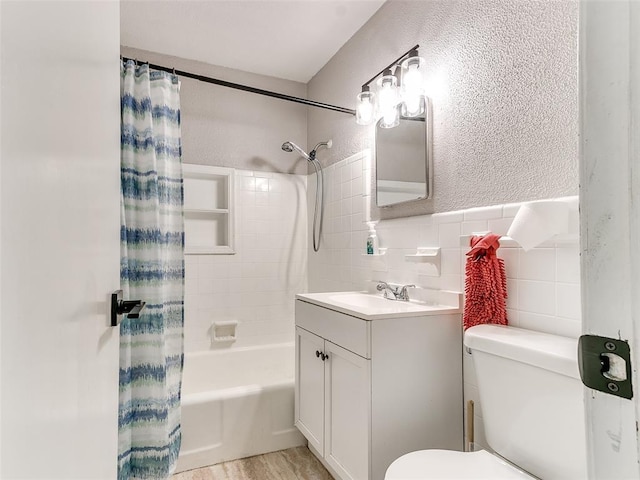 full bathroom with tile walls, toilet, shower / tub combo with curtain, and vanity