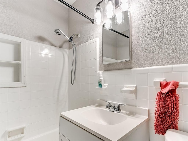 full bathroom featuring toilet, vanity, tile walls, and tub / shower combination