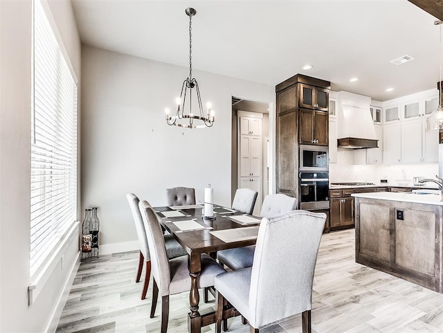 dining room with a notable chandelier, plenty of natural light, and light hardwood / wood-style flooring