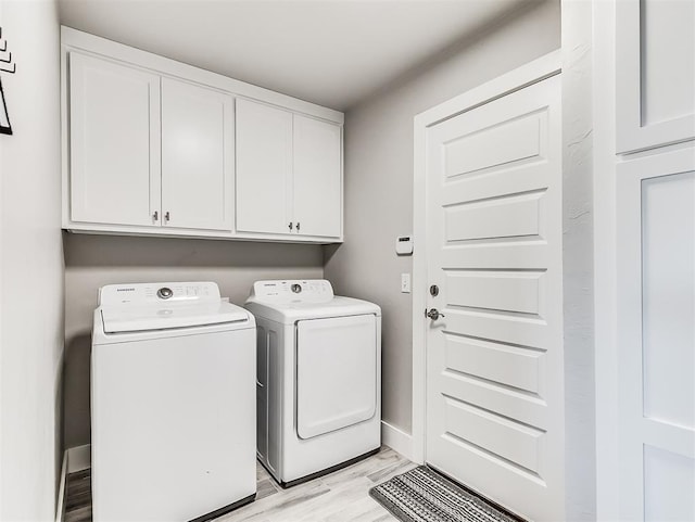 washroom featuring cabinets, washer and clothes dryer, and light wood-type flooring