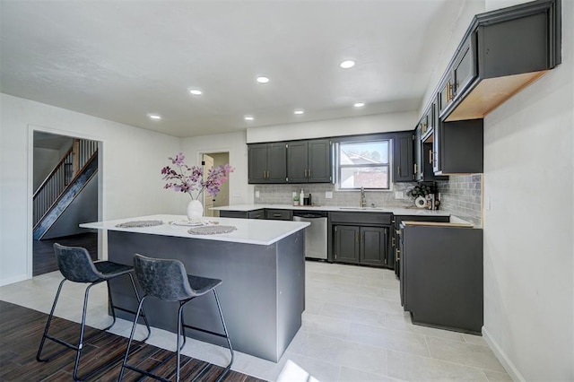 kitchen with dishwasher, a breakfast bar, tasteful backsplash, gray cabinetry, and sink