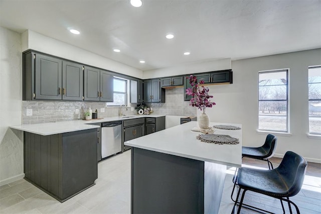 kitchen with kitchen peninsula, dishwasher, a breakfast bar, gray cabinets, and sink