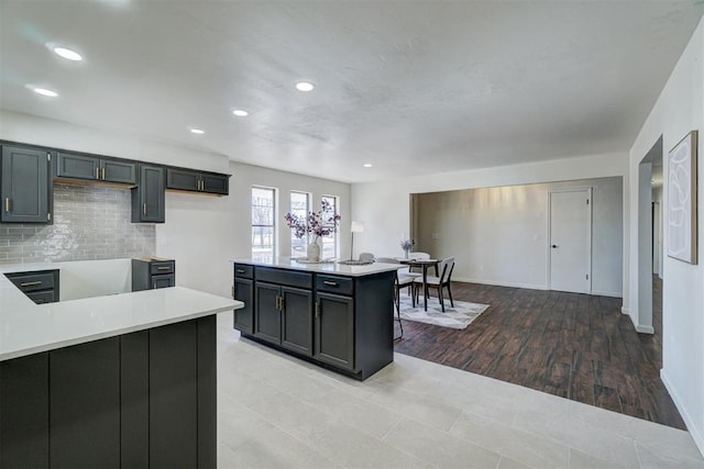 kitchen with decorative backsplash, light wood-type flooring, and kitchen peninsula