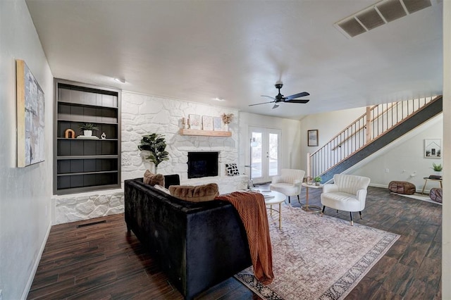 living room featuring ceiling fan, dark hardwood / wood-style flooring, french doors, a fireplace, and built in features