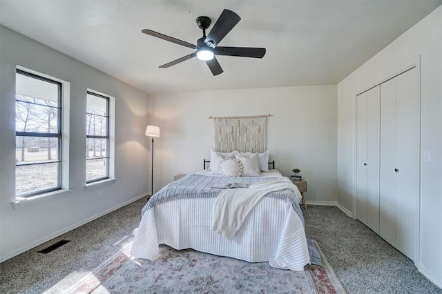 bedroom featuring light colored carpet, ceiling fan, and a closet