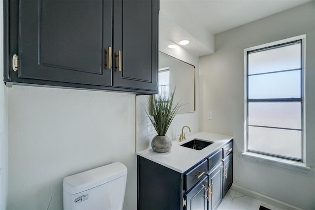 bathroom featuring toilet, vanity, and plenty of natural light