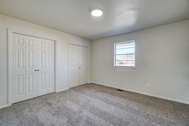 unfurnished bedroom with multiple closets and carpet