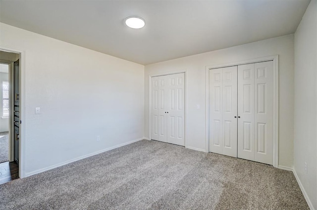 unfurnished bedroom with two closets and carpet floors