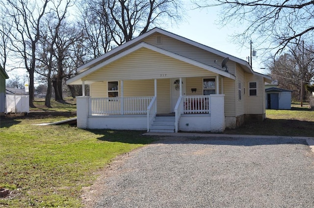 bungalow featuring a porch, a front lawn, and a shed