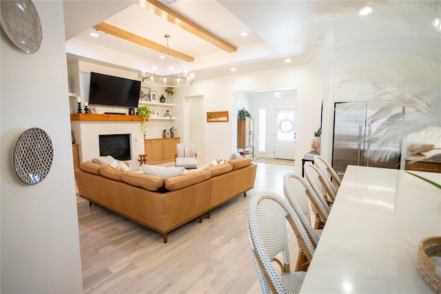 living room featuring built in shelves, a tray ceiling, light hardwood / wood-style flooring, and a notable chandelier