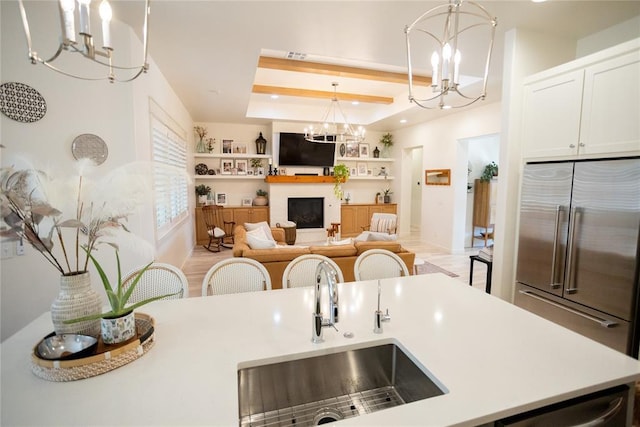 kitchen featuring appliances with stainless steel finishes, sink, hanging light fixtures, a notable chandelier, and a raised ceiling