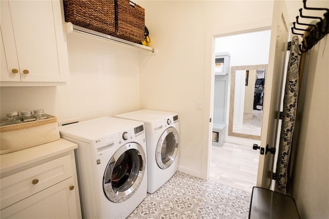 washroom featuring separate washer and dryer, light tile patterned floors, and cabinets