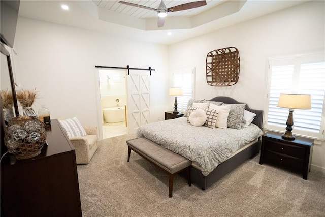 bedroom with ensuite bath, ceiling fan, carpet flooring, a tray ceiling, and a barn door