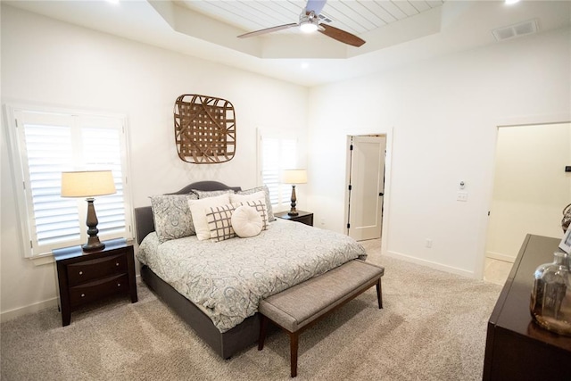 carpeted bedroom featuring a raised ceiling and ceiling fan