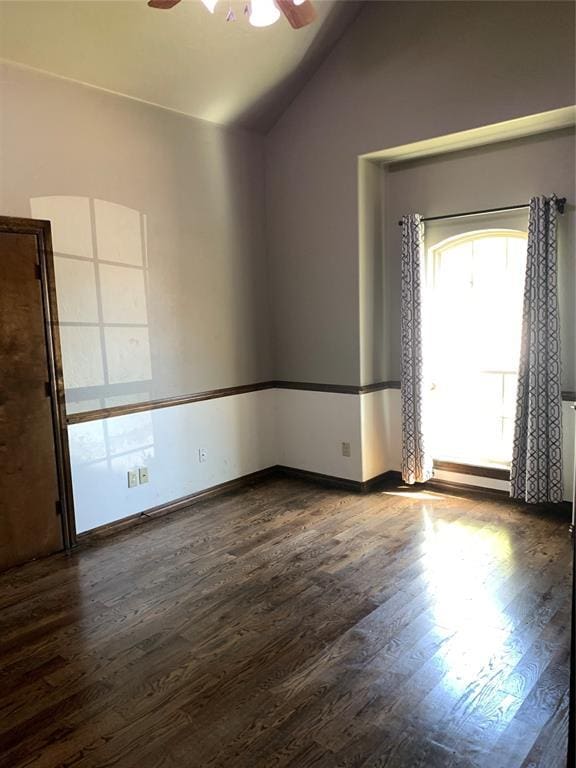 empty room featuring lofted ceiling, ceiling fan, and dark wood-type flooring