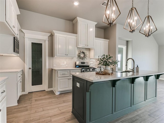 kitchen with white cabinets, stainless steel range, and an island with sink