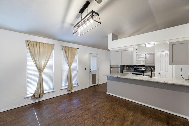 kitchen with dark wood-type flooring, sink, stainless steel appliances, light stone countertops, and decorative backsplash