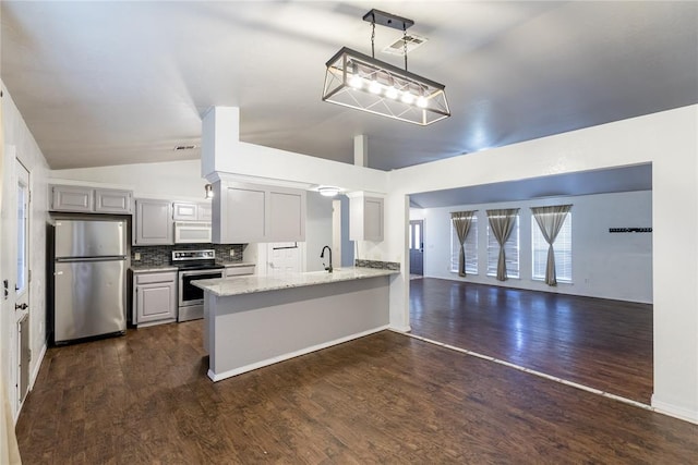 kitchen with appliances with stainless steel finishes, gray cabinetry, hanging light fixtures, vaulted ceiling, and kitchen peninsula