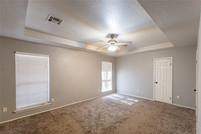 carpeted spare room featuring ceiling fan, a tray ceiling, and a textured ceiling