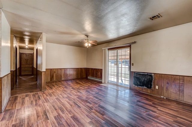 unfurnished living room with ceiling fan, a baseboard heating unit, dark wood-type flooring, and a textured ceiling