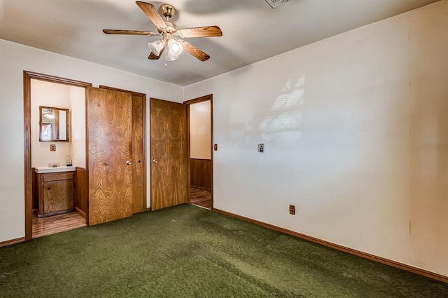 unfurnished bedroom featuring ceiling fan, wooden walls, and dark carpet