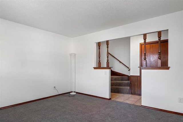 unfurnished room featuring a textured ceiling and light carpet