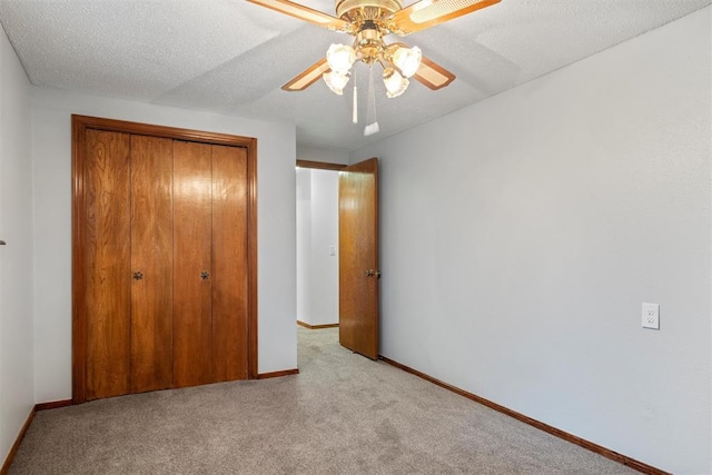 unfurnished bedroom with a textured ceiling, light colored carpet, a closet, and ceiling fan