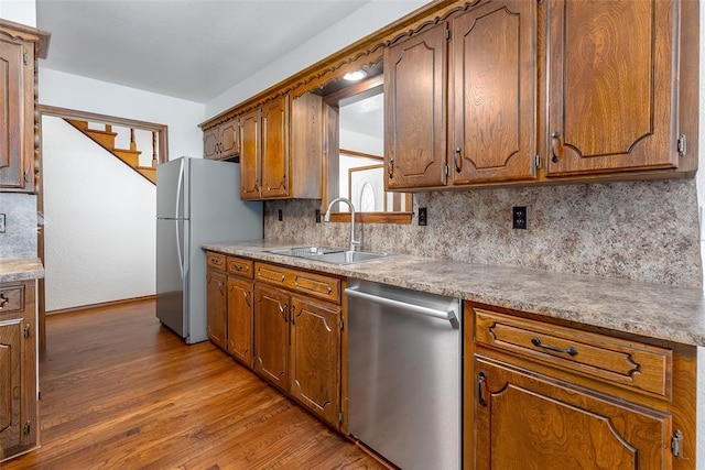 kitchen featuring sink, stainless steel appliances, light hardwood / wood-style flooring, and decorative backsplash