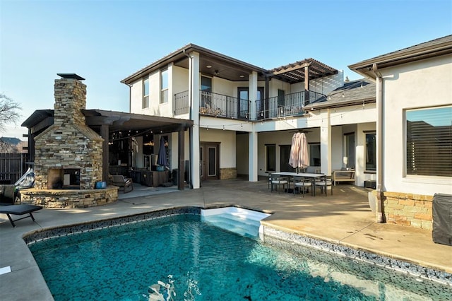 rear view of property with a patio and an outdoor stone fireplace