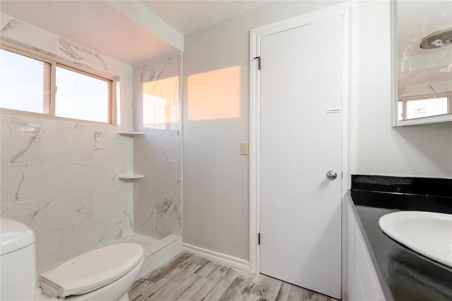 bathroom featuring toilet, vanity, a tile shower, and hardwood / wood-style floors