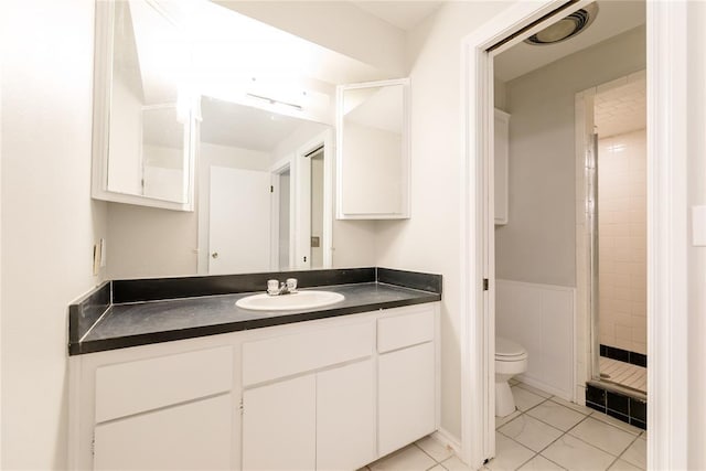 bathroom featuring tile patterned floors, toilet, vanity, and a tile shower