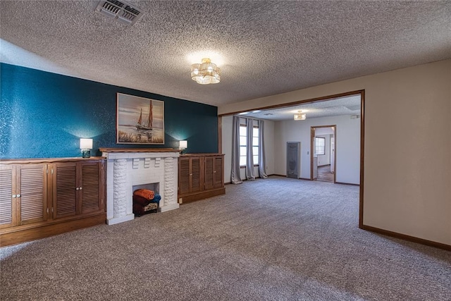 unfurnished living room featuring carpet, a brick fireplace, and a textured ceiling