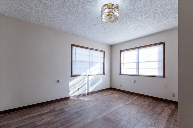 unfurnished room with dark hardwood / wood-style flooring, a textured ceiling, and a notable chandelier