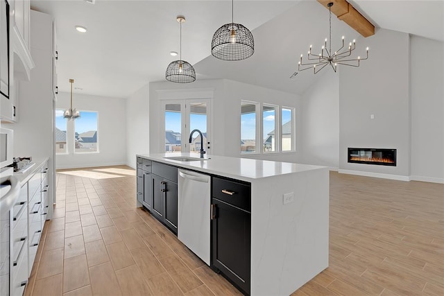 kitchen with sink, a kitchen island with sink, hanging light fixtures, lofted ceiling with beams, and stainless steel dishwasher