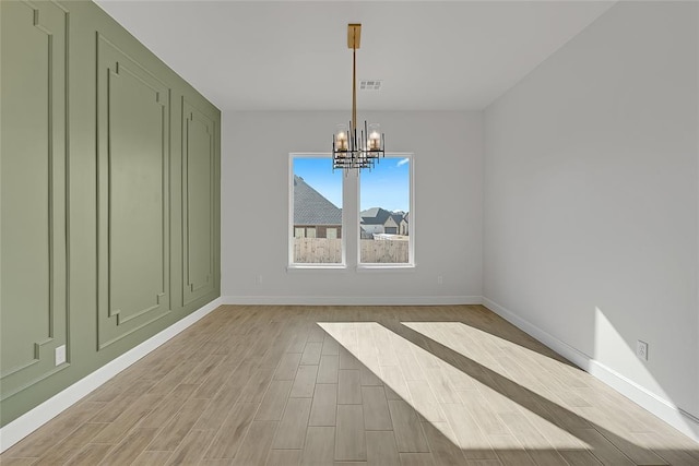 unfurnished dining area with an inviting chandelier and light hardwood / wood-style flooring