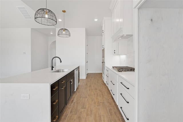 kitchen with sink, hanging light fixtures, a center island with sink, appliances with stainless steel finishes, and white cabinets