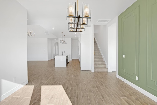 unfurnished living room featuring sink and a chandelier