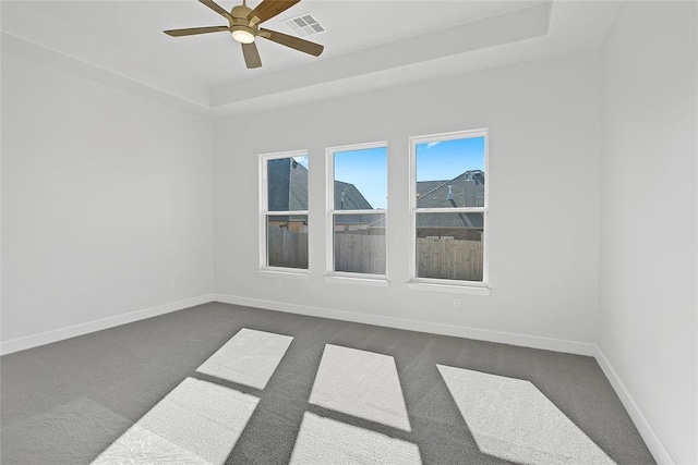 carpeted spare room featuring ceiling fan and a tray ceiling