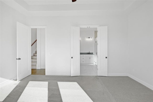 unfurnished bedroom featuring light carpet and ensuite bath