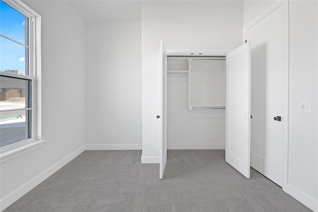 unfurnished bedroom featuring multiple windows, light colored carpet, and a closet