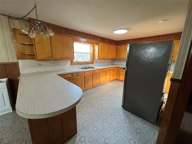 kitchen with sink, an inviting chandelier, stainless steel refrigerator, and kitchen peninsula