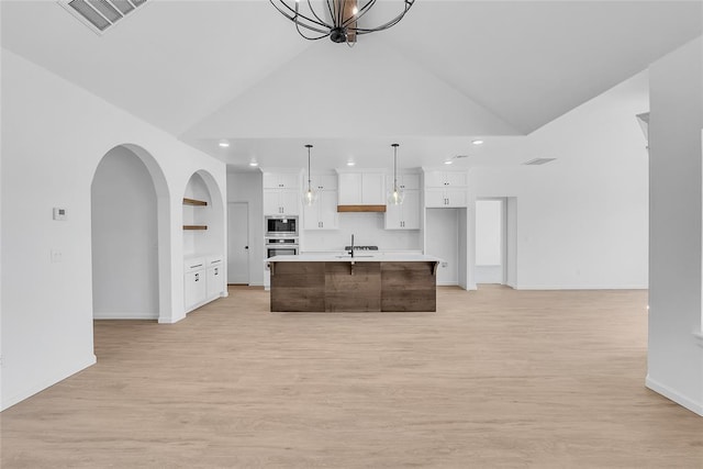 kitchen with white cabinetry, decorative light fixtures, an island with sink, and appliances with stainless steel finishes