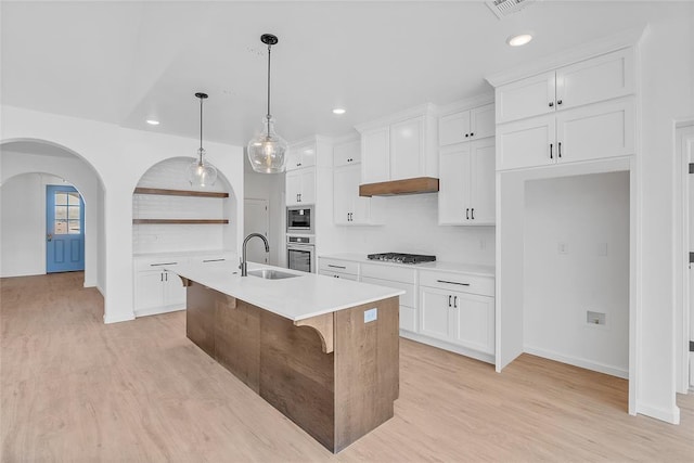 kitchen with white cabinetry, sink, decorative light fixtures, and an island with sink