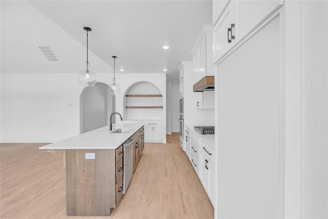 kitchen featuring stainless steel appliances, hanging light fixtures, a center island with sink, and white cabinets