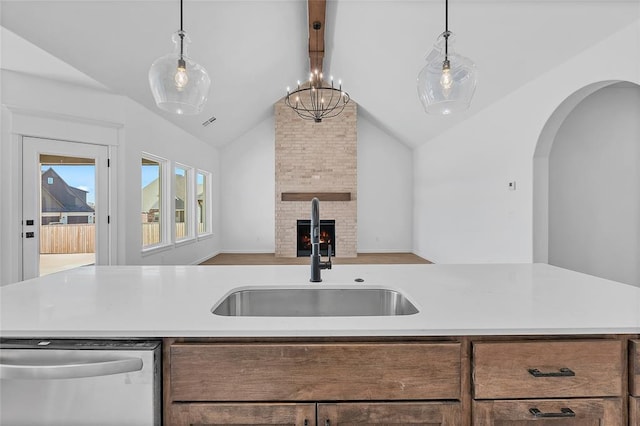 kitchen featuring sink, decorative light fixtures, lofted ceiling with beams, stainless steel dishwasher, and a large fireplace