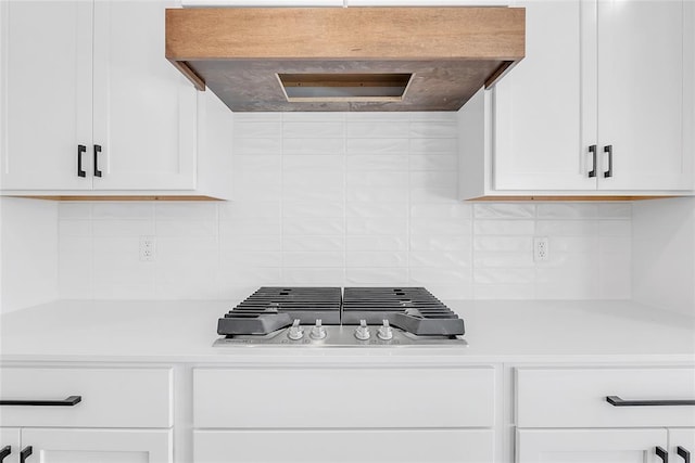 kitchen featuring premium range hood, stainless steel gas cooktop, decorative backsplash, and white cabinets