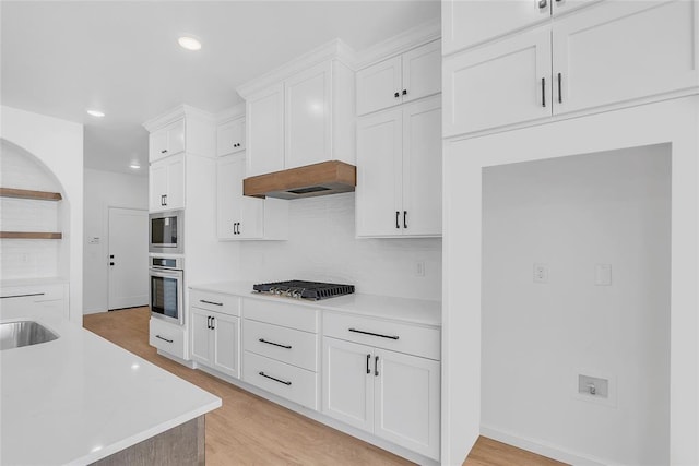 kitchen with stainless steel appliances, light hardwood / wood-style flooring, and white cabinets