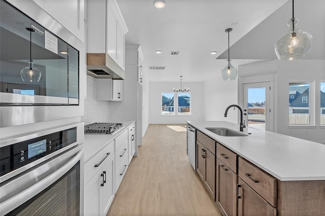 kitchen with sink, white cabinetry, a center island with sink, appliances with stainless steel finishes, and decorative backsplash