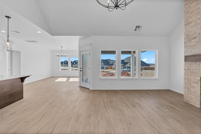 unfurnished living room with lofted ceiling, light hardwood / wood-style flooring, and a notable chandelier