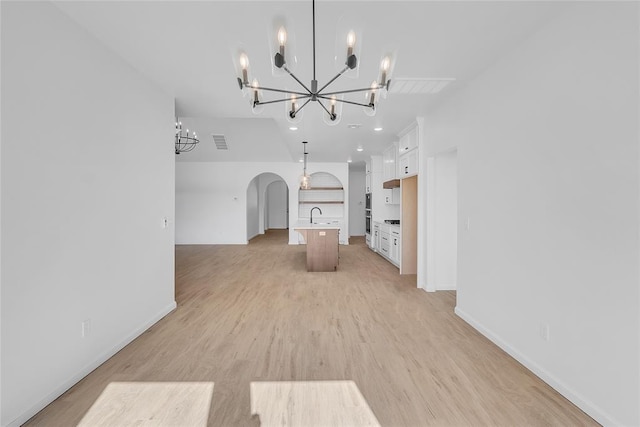 unfurnished living room with sink, a chandelier, and light wood-type flooring